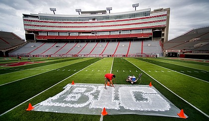 In this Thursday, Oct. 6, 2011 file photo, Turf manager Jared Hertzel touches up the newly-painted Big Ten conference logo on the football field at Memorial Stadium in Lincoln, Neb. 
