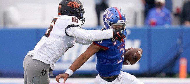 Kansas quarterback Miles Kendrick tries to avoid pressure from Oklahoma State's Devin Harper during a Jayhawks loss on Oct. 3, 2020.