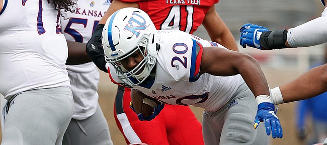 Kansas' Daniel Hishaw Jr. (20) breaks the tackle by Texas Tech's Tre'Jon Lewis (77) during the first half of an NCAA college football game Saturday, Dec. 5, 2020, in Lubbock, Texas. (AP Photo/Brad Tollefson)