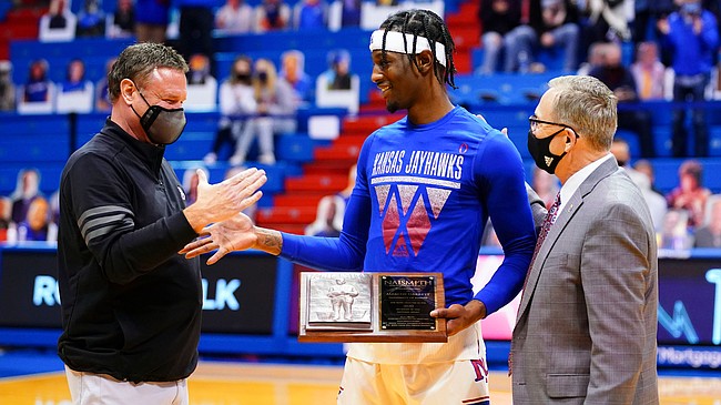 Kansas head coach Bill Self slaps hands with Kansas guard Marcus Garrett (0) after Garrett received the Naismith Defensive Player of the Year trophy prior to tipoff on Friday, Dec. 11, 2020 at Allen Fieldhouse. At right is athletic director Jeff Long.