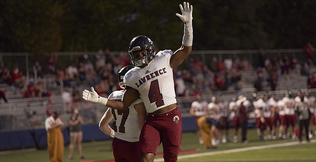 Lawrence High senior Devin Neal (4) celebrates his touchdown with teammate Ben King (17) Friday night at St. Thomas Aquinas. The Lions handed the Saints their first home loss since 2017.