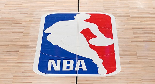 In this Aug. 28, 2020, file photo, the NBA logo in an empty basketball arena in Lake Buena Vista, Fla. (AP Photo/Ashley Landis, Pool, File)