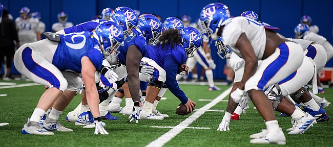 Kansas football players line up and prepare for a snap during a spring practice on April 9, 2021, in the Jayhawks' indoor practice facility. 