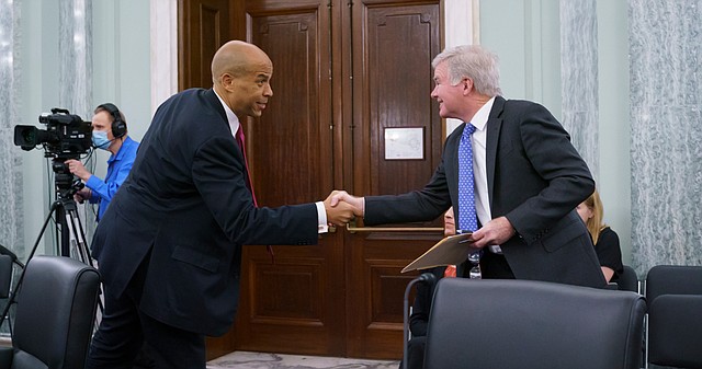 Sen. Cory Booker, D-N.J., left, greets NCAA President Mark Emmert, as the Senate Commerce, Science, and Transportation Committee holds a hearing on student athlete compensation and federal legislative proposals to enable athletes participating in collegiate sports to monetize their name, image, and likeness, at the Capitol in Washington, Wednesday, June 9, 2021. 
