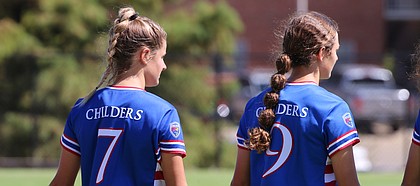 Sisters and Kansas soccer teammates Raena (No. 7) and Rylan Childers (No. 9) hold hands on the sideline before a game.