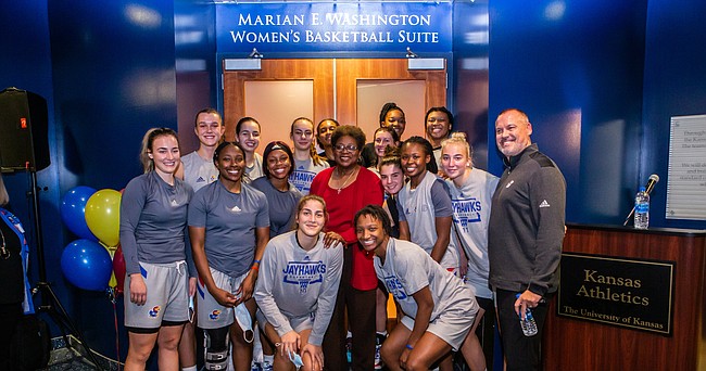 Former Kansas women's basketball coach Marian Washington, in red, joins the current KU team for a photo following the unveiling of the Marian E. Washington Women's Basketball Suite on Friday, Oct. 22, 2021 at Allen Fieldhouse.