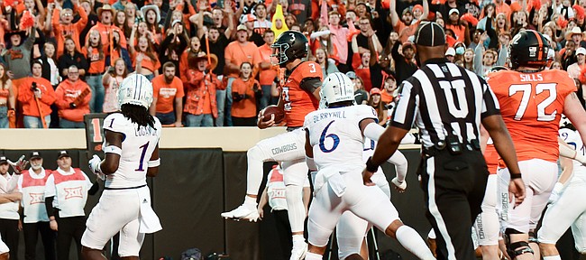 Oklahoma State quarterback Spencer Sanders (3) jumps across the goal line while Kansas safety Kenny Logan Jr. (1) and linebacker Taiwan Berryhill (6) watch during the first quarter of an NCAA college football game Saturday, Oct. 30, 2021, in Stillwater, Okla.
