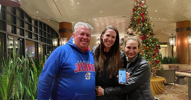 KU fans and family members, Tony Gourlay, left, Sydney Gourlay, center, and Jillian James, huddle together while displaying a photo of son and brother A.J. Gourlay at the St. Julien Hotel in Boulder, Colorado, on Tuesday, Dec. 21, 2021.
