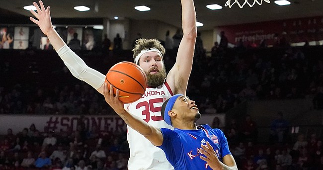 Kansas guard Dajuan Harris Jr. (3) goes to the basket in front of Oklahoma forward Tanner Groves (35) in the first half of an NCAA college basketball game Tuesday, Jan. 18, 2022, in Norman, Okla. (AP Photo/Sue Ogrocki)