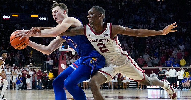 Kansas guard Christian Braun, left, is fouled by Oklahoma guard Umoja Gibson (2) in the second half of an NCAA college basketball game Tuesday, Jan. 18, 2022, in Norman, Okla. (AP Photo/Sue Ogrocki)