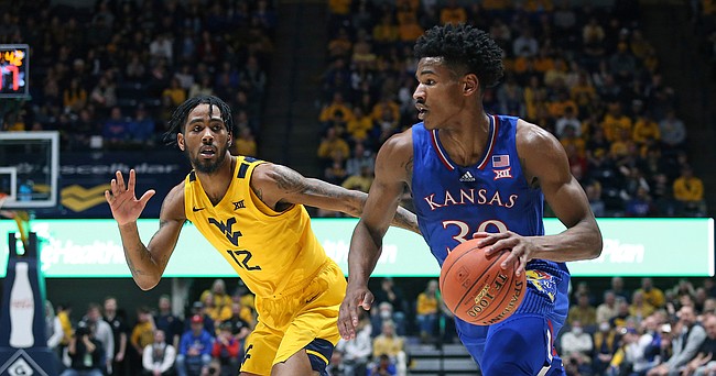 Kansas guard Ochai Agbaji, right, is defended by West Virginia guard Taz Sherman (12) during the first half of an NCAA college basketball game in Morgantown, W.Va., Saturday, Feb. 19, 2022.