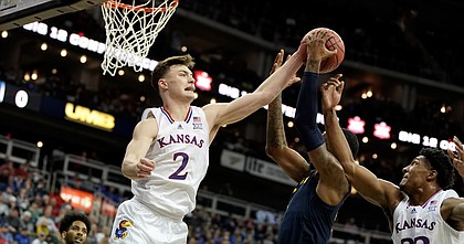 Kansas guard Christian Braun (2) and Kansas forward David McCormack (33) look to knock a ball away from West Virginia forward Gabe Osabuohien (3) during the first half on Thursday, March 10, 2022 at T-Mobile Center in Kansas City.