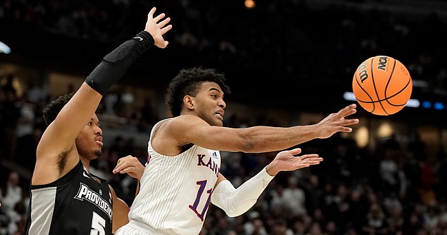 Kansas guard Remy Martin (11) kicks out a pass to the wing as he is defended by Providence forward Ed Croswell (5) during the second half on Friday, March 25, 2022 at United Center in Chicago.