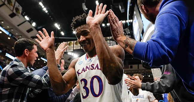 Kansas guard Ochai Agbaji slaps hands with fans as the Jayhawks leave the court following their 66-61 victory over Providence on Friday, March 25, 2022 at United Center in Chicago.