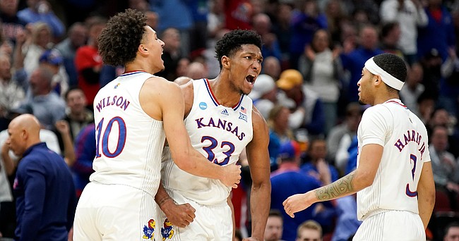 Kansas forward David McCormack (33) celebrates with Kansas forward Jalen Wilson (10) and Kansas guard Dajuan Harris Jr. (3) after an and-one bucket during the second half on Sunday, March 27, 2022 at United Center in Chicago. The Jayhawks defeated the Hurricanes, 76-50 to advance to the Final Four.