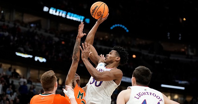 Kansas guard Ochai Agbaji (30) elevates for a shot over Miami forward Sam Waardenburg (21) and Miami guard Kameron McGusty (23) during the second half on Sunday, March 27, 2022 at United Center in Chicago. The Jayhawks defeated the Hurricanes, 76-50 to advance to the Final Four.