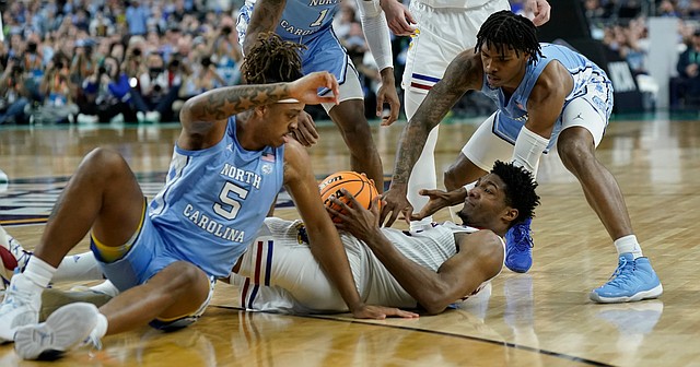 Kansas forward David McCormack (33) wrestles on the floor for a ball with North Carolina forward Armando Bacot (5) and North Carolina guard Caleb Love (2) during the first half of the NCAA National Championship game on Monday, April 4, 2022 at Caesars Superdome in New Orleans.