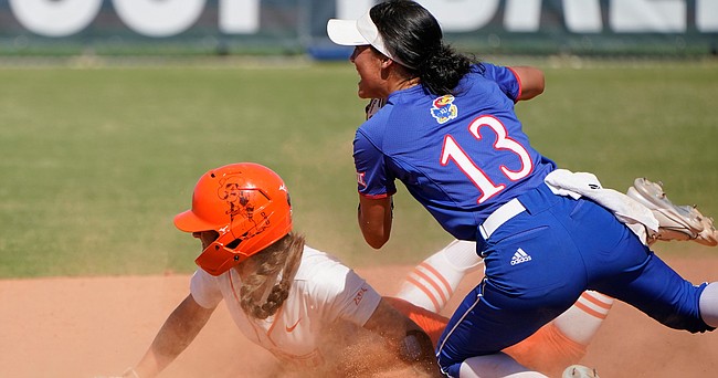 Oklahoma State's Kiley Naomi, left, and Kansas' Haleigh Harper (13) look to an umpire for the call as Naomi steals second base during the fifth inning of an NCAA college softball game in the Big 12 tournament Thursday, May 12, 2022, in Oklahoma City. (AP Photo/Sue Ogrocki)