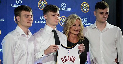 Denver Nuggets guard Christian Braun, second from left, holds up his jersey for a photo with his brothers Parker, left, and Landon, right, and mother, Lisa, after being introduced to the media during a news conference on June 27, 2022, in Denver.