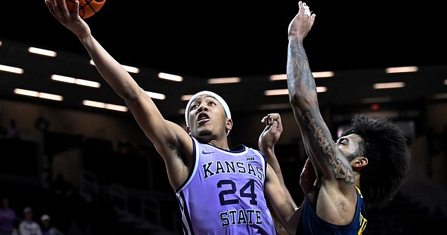 Kansas State guard Nijel Pack drives past West Virginia forward Isaiah Cottrell during game in Manhattan, Kan., on Feb. 14, 2022. Pack made one of the first big splashes of the NIL era when he received a six-figure endorsement deal shortly after transferring to Miami in April.