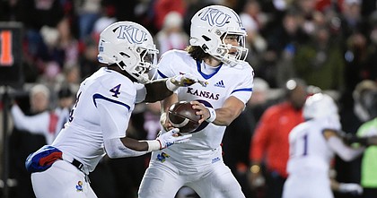 Kansas quarterback Jason Bean hands off to running back Devin Neal (4) during the first half of the team's NCAA college football game against Texas Tech on Saturday, Nov. 12, 2022, in Lubbock, Texas. (AP Photo/Justin Rex)