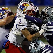Kansas wide receiver Lawrence Arnold (2) is stopped by Kansas State safety VJ Payne (19) linebacker Daniel Green (22) and safety Drake Cheatum (21) after catching a pass for a first down during the first quarter of an NCAA college football game on Saturday, Nov. 26, 2022, in Manhattan, Kan. (AP Photo/Colin E. Braley)