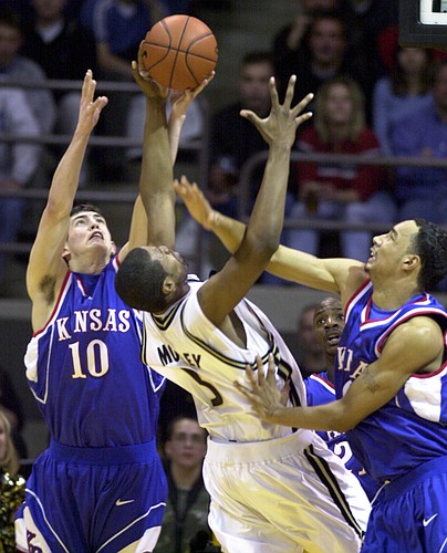 Kansas University players Kirk Hinrich, left, and Drew Gooden, try to steal the ball from Colorado's Jamahl Mosley. KU defeated Colorado, 84-69, to register the 1,700th victory in program history.