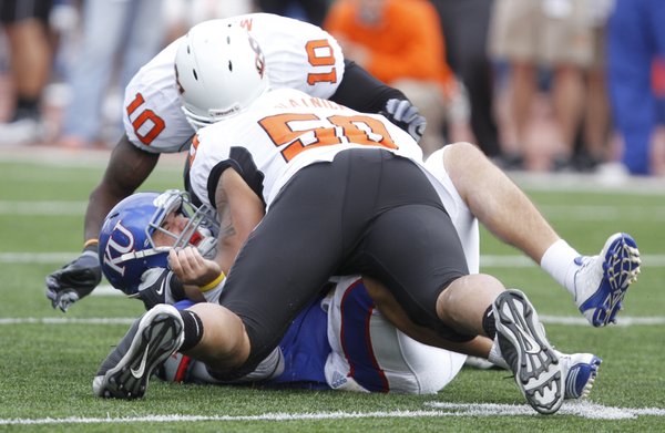 Kansas quarterback Quinn Mecham is driven to the turf on a sack by Oklahoma State defensive end Jamie Blatnick (50) during the third quarter, Saturday, Nov. 20, 2010 at Kivisto Field. Also assisting on the stop is OSU safety Markelle Martin.
