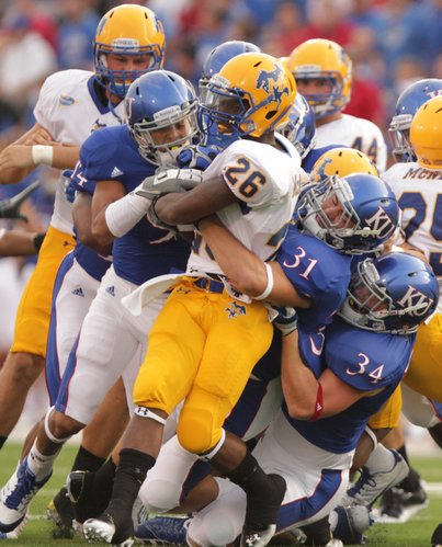 Kansas special teams players Keeston Terry, left, Ben Heeney (31) and Huldon Tharp (34) collapse on McNeese State returner Champlain Babin during the first quarter on Saturday, Sept. 3, 2011 at Kivisto Field.