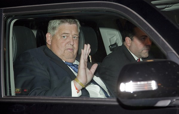 Charlie Weis, 55, waves to media members at the Lawrence Airport on Thursday night around 8:30 p.m. after arriving in town with Kansas athletic director Sheahon Zenger, at right. Weis has agreed to become the 37th head football coach in KU history.