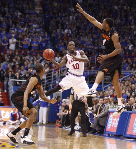 Kansas guard Tyshawn Taylor passes through a trap by Oklahoma State defenders Markel Brown, left, and Brian Williams during the second half on Saturday, Feb. 11, 2012 at Allen Fieldhouse.