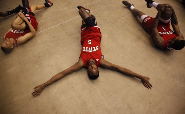 North Carolina State forward C.J. Leslie stretches out between teammates Tyler Harris, left, and Richard Howell during a day of press conferences and practices at the Edward Jones Dome in St. Louis.