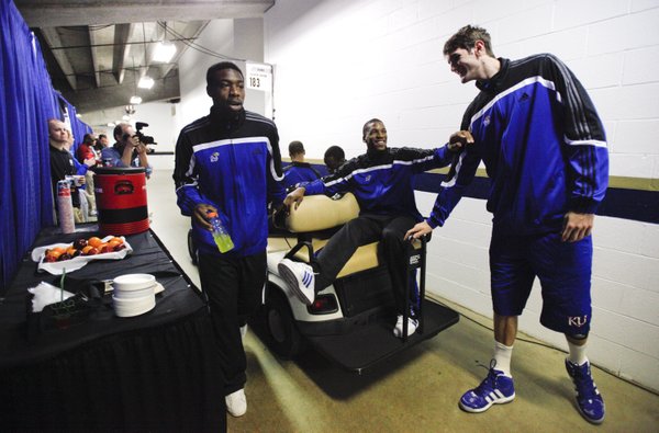 Kansas forward Thomas Robinson, center, jokingly pushes center Jeff Withey away from his golf cart as the players prepare to be shuttled to interviews on Saturday, March 24, 2012 at the Edward Jones Dome in St. Louis. At left is KU guard Elijah Johnson.