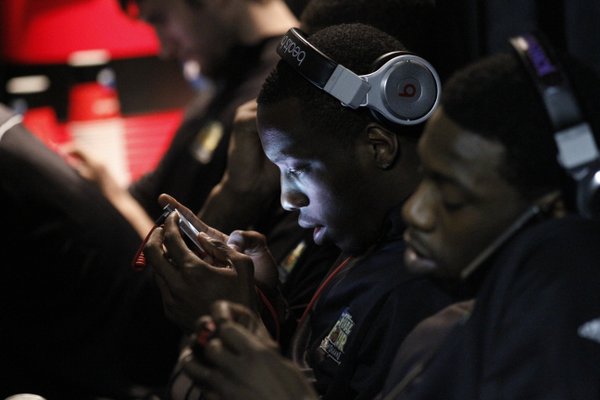 Tyshawn Taylor, center, and Elijah Johnson text and listen to music in an interview waiting room during press conferences in the Superdome Sunday.