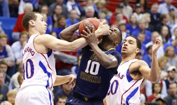 Kansas guard Evan Manning fouls West Virginia guard Eron Harris on the drive during the second half on Saturday, March 2, 2013 at Allen Fieldhouse. At right is KU guard Niko Roberts.