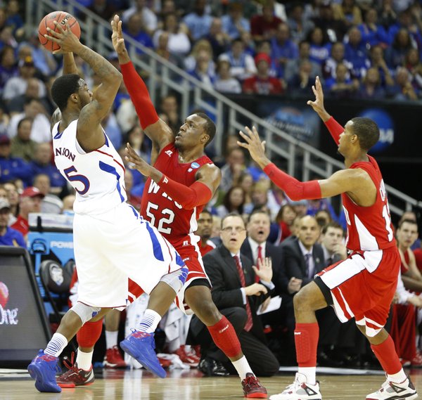 Kansas guard Elijah Johnson is defended by Western Kentucky players T.J. Price, left, and Jamal Crook during the first half on Friday, March 22, 2013 at the Sprint Center in Kansas City, Mo.