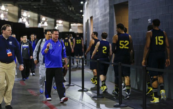 Kansas head coach Bill Self lifts his water bottle in acknowledgement of the Michigan Wolverines players as they head to their locker room after a practice at Cowboys Stadium in Arlington, Texas on Thursday, March 28, 2013.