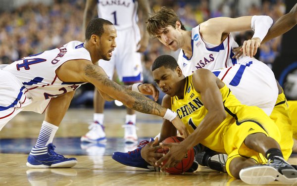 Kansas players Travis Releford, left, and Jeff Withey scramble for a tie up with Michigan forward Glenn Robinson III during the second half on Friday, March 29, 2013 at Cowboys Stadium in Arlington, Texas.