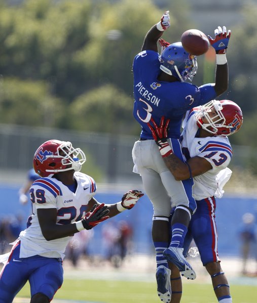 Kansas running back Tony Pierson can't hang on to a catch as he is wrapped up by Louisiana Tech defenders Le'Vander Liggins (13) and Xavier Woods during the second quarter on Saturday, Sept. 21, 2013 at Memorial Stadium.