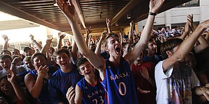 Kansas University junior Eli Birzer, Hutchinson, Kan., center, raises his arms in jubilation as Jayhawk newcomers Andrew Wiggins and Joel Embiid peek out of the fieldhouse to pump up the crowd before the doors opened for Late Night in the Phog, Friday, Oct. 4, 2013.