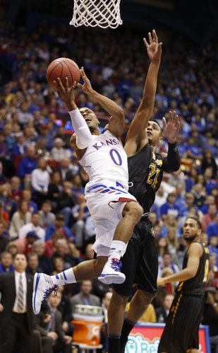 Kansas guard Frank Mason hangs for a shot as he is fouled by Towson forward Jerrelle Benimon during the first half on Friday, Nov. 22, 2013 at Allen Fieldhouse.