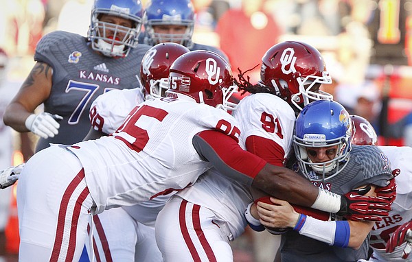 Kansas quarterback Jake Heaps is sacked by Oklahoma defenders Charles Tapper (91) and Geneo Grissom on the Jayhawks' last drive of the game, Saturday, Oct. 19, 2013 at Memorial Stadium.