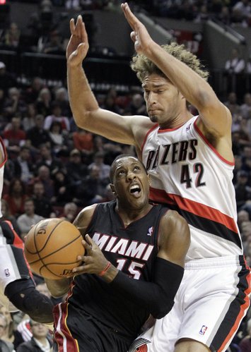 Miami Heat guard Mario Chalmers, left, drives against Portland Trail Blazers center Robin Lopez during the first half of an NBA basketball game in Portland, Ore., Saturday, Dec. 28, 2013. (AP Photo/Don Ryan)
