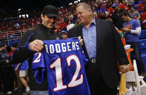 Green Bay Packers quarterback Aaron Rodgers receives a Kansas football jersey from head coach Charlie Weis prior to Saturday's basketball game against Oklahoma State at Allen Fieldhouse.