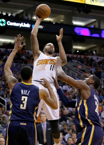 Phoenix Suns' Markieff Morris (11) gets off a shot and scores over Indiana Pacers' George Hill (3) and Ian Mahinmi, right, during the second half of an NBA basketball game Wednesday, Jan. 22, 2014, in Phoenix. The Suns defeated the Pacers 124-100. (AP Photo/Ross D. Franklin)
