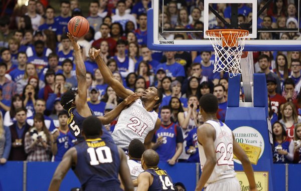 Kansas center Joel Embiid swats away a shot from West Virginia forward Devin Williams during the second half on Saturday, Feb. 8, 2014 at Allen Fieldhouse.