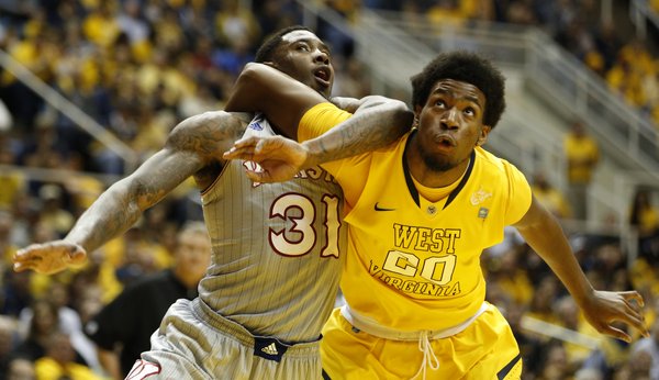Kansas forward Jamari Traylor and West Virginia forward Brandon Watkins get tangled as they battle for a rebound during the first half on Saturday, March 8, 2014 at WVU Coliseum in Morgantown, West Virginia.