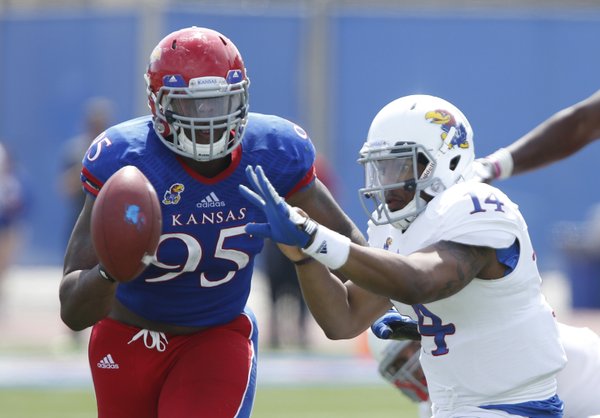White Team quarterback Michael Cummings pitches the ball to a teammate as Blue Team defensive lineman Andrew Bolton closes in during the second half of the Kansas Spring Game on Saturday, April 12, 2014 at Memorial Stadium. Nick Krug/Journal-World Photo