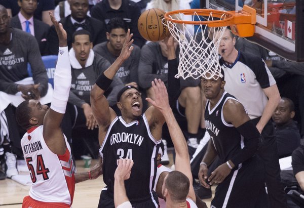 Brooklyn Nets' Paul Pierce, center, drives to the net against Toronto Raptors Patrick Patterson, left, during the first half of Game 1 of an opening-round NBA basketball playoff series, in Toronto on Saturday, April 19, 2014. (AP Photo/The Canadian Press, Darren Calabrese)

