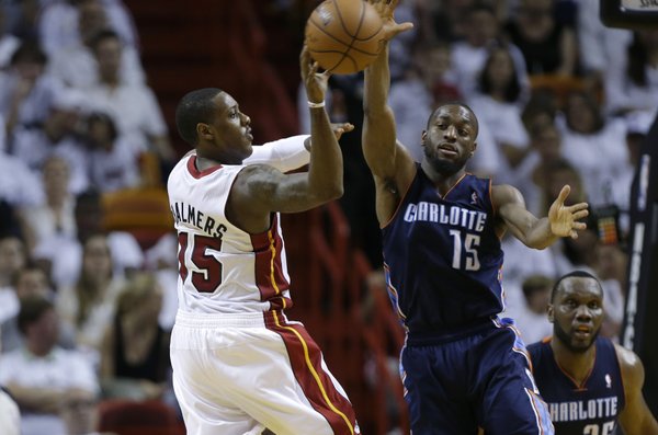 Miami Heat's Mario Chalmers (15) passes the ball as Charlotte Bobcats' Kemba Walker (15) defends during the second half in Game 1 of an opening-round NBA basketball playoff series, Sunday, April 20, 2014, in Miami. The Heat defeated the Bobcats 99-88. (AP Photo/Lynne Sladky)